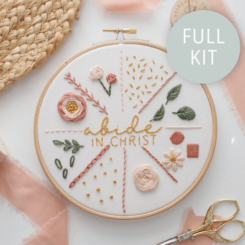Finished stitch practice hoop: "abide in Christ" surrounded by flowers, leaves and stitch samples