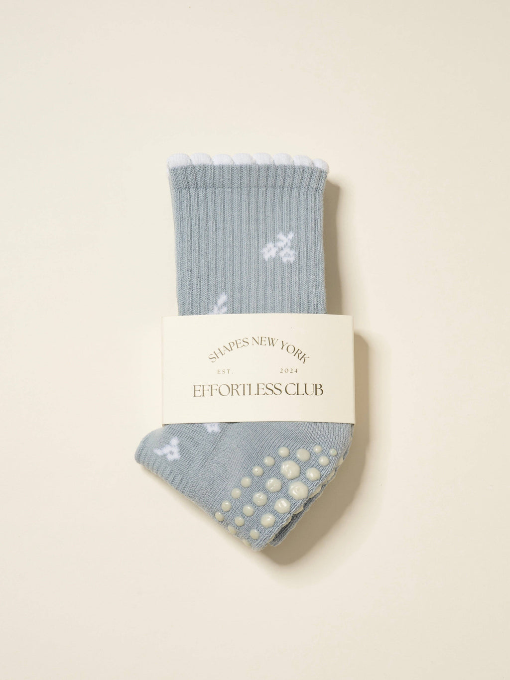 Pale blue grip socks with white snowflakes and a white scalloped cuff, folded in their band