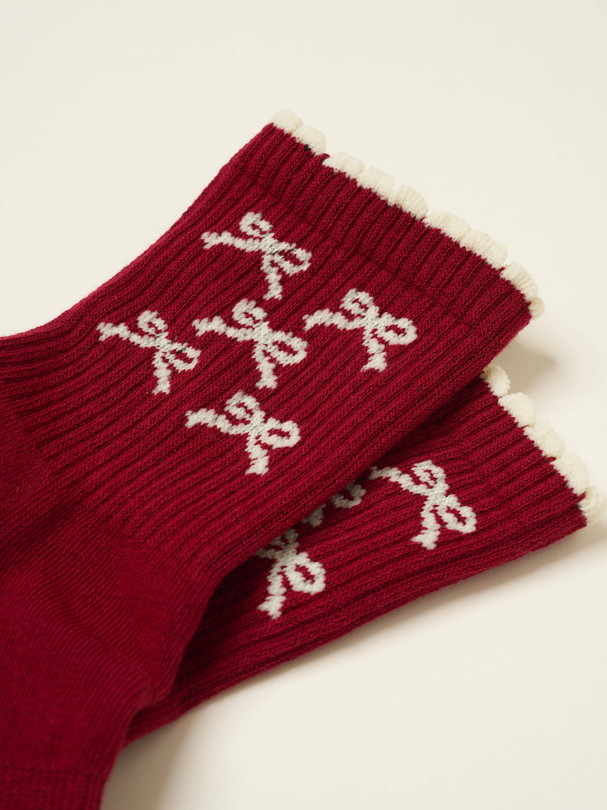 Close view of the cream bows on the ribbed burgundy cuff