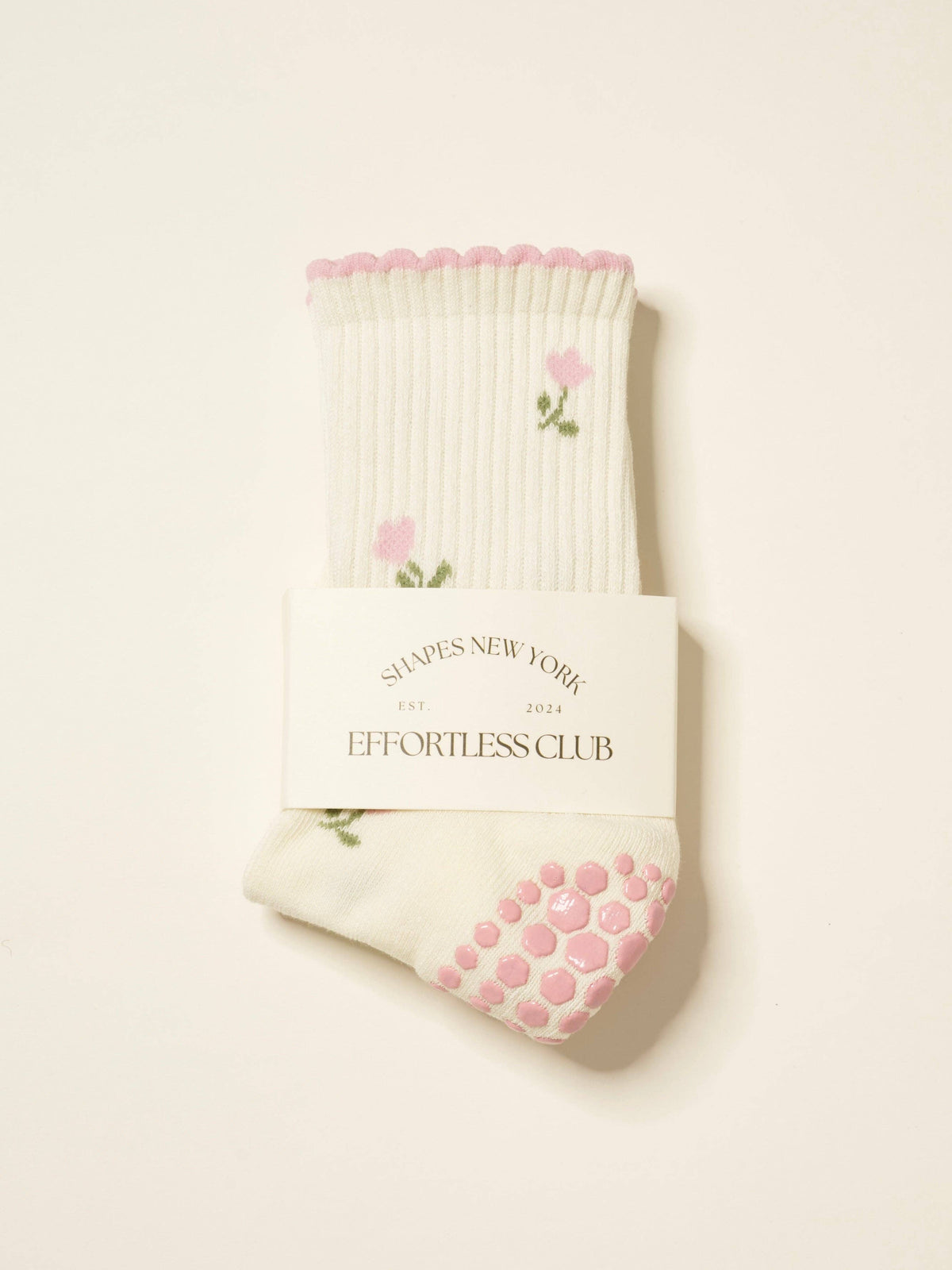 Cream grip socks with pink tulips and a pink scalloped cuff, folded in their band