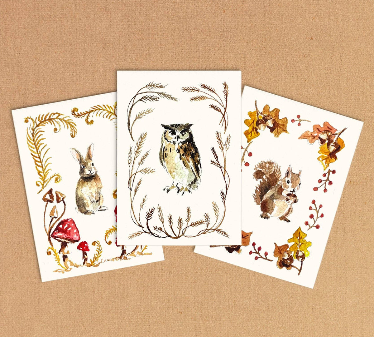 Three finished mini paintings: a rabbit with mushrooms, an owl in a wheat wreath and a squirrel with autumn leaves