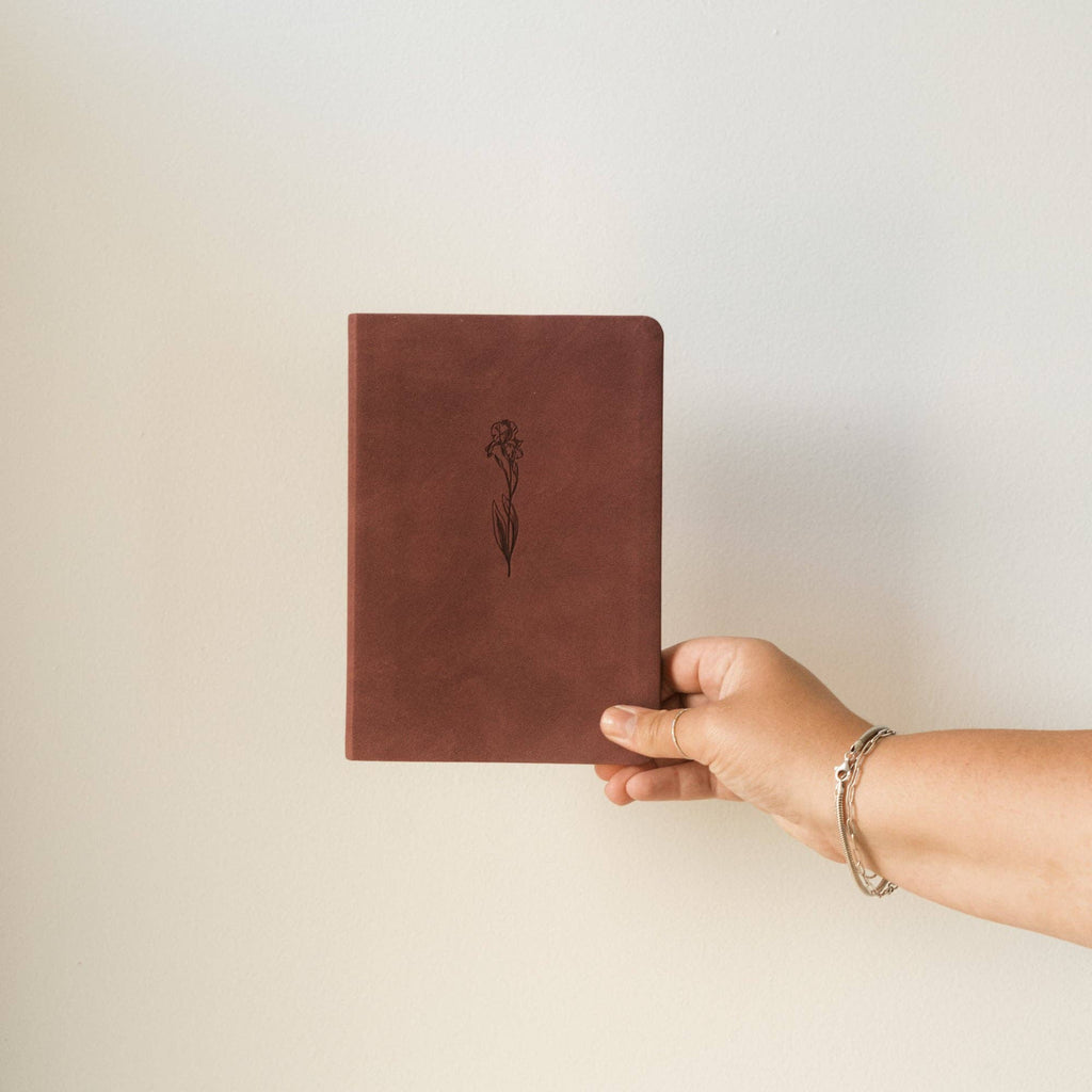 Hand holding the berry iris notebook