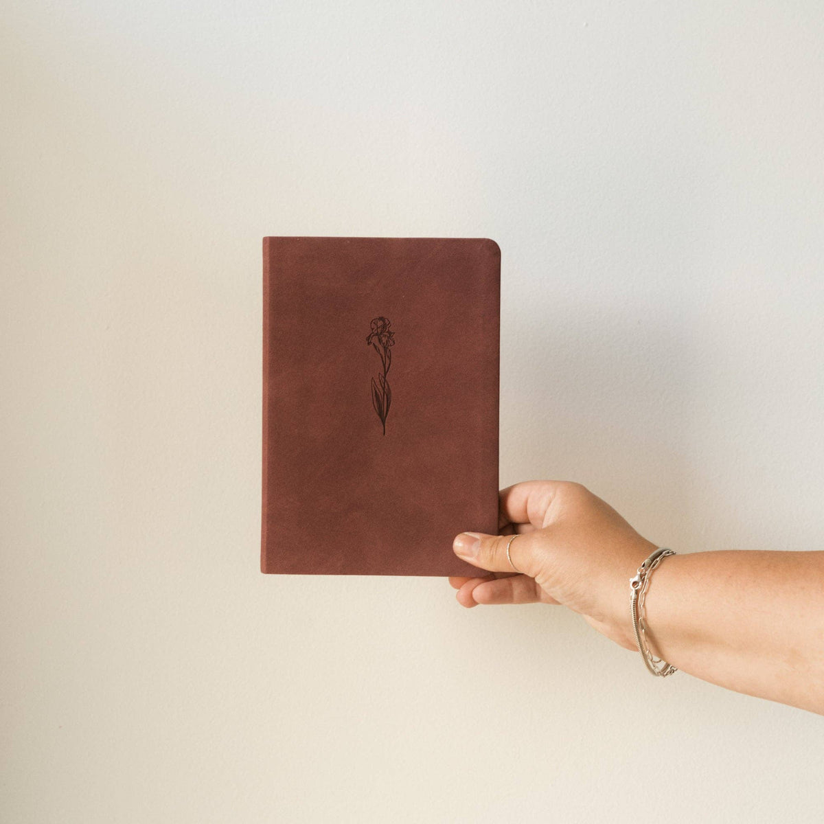 Hand holding the berry iris notebook