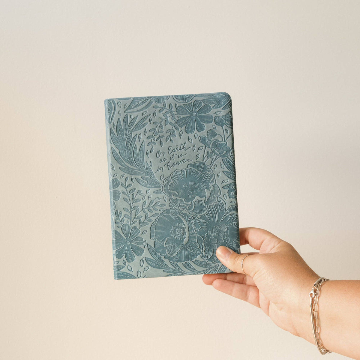 Hand holding the teal floral notebook