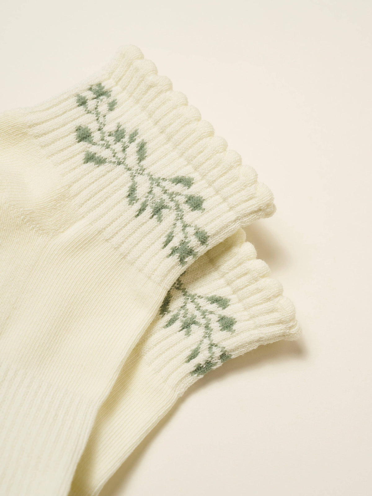 Close view of the green leafy garland on the scalloped cream cuff
