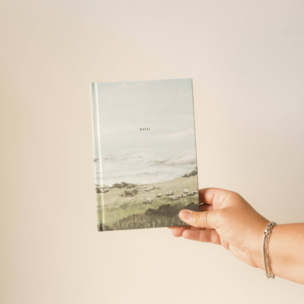 Hand holding the green hills notebook