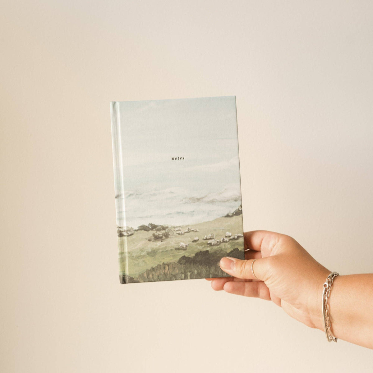 Hand holding the green hills notebook