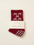 Burgundy grip socks with cream bows and a cream scalloped cuff, folded in their band