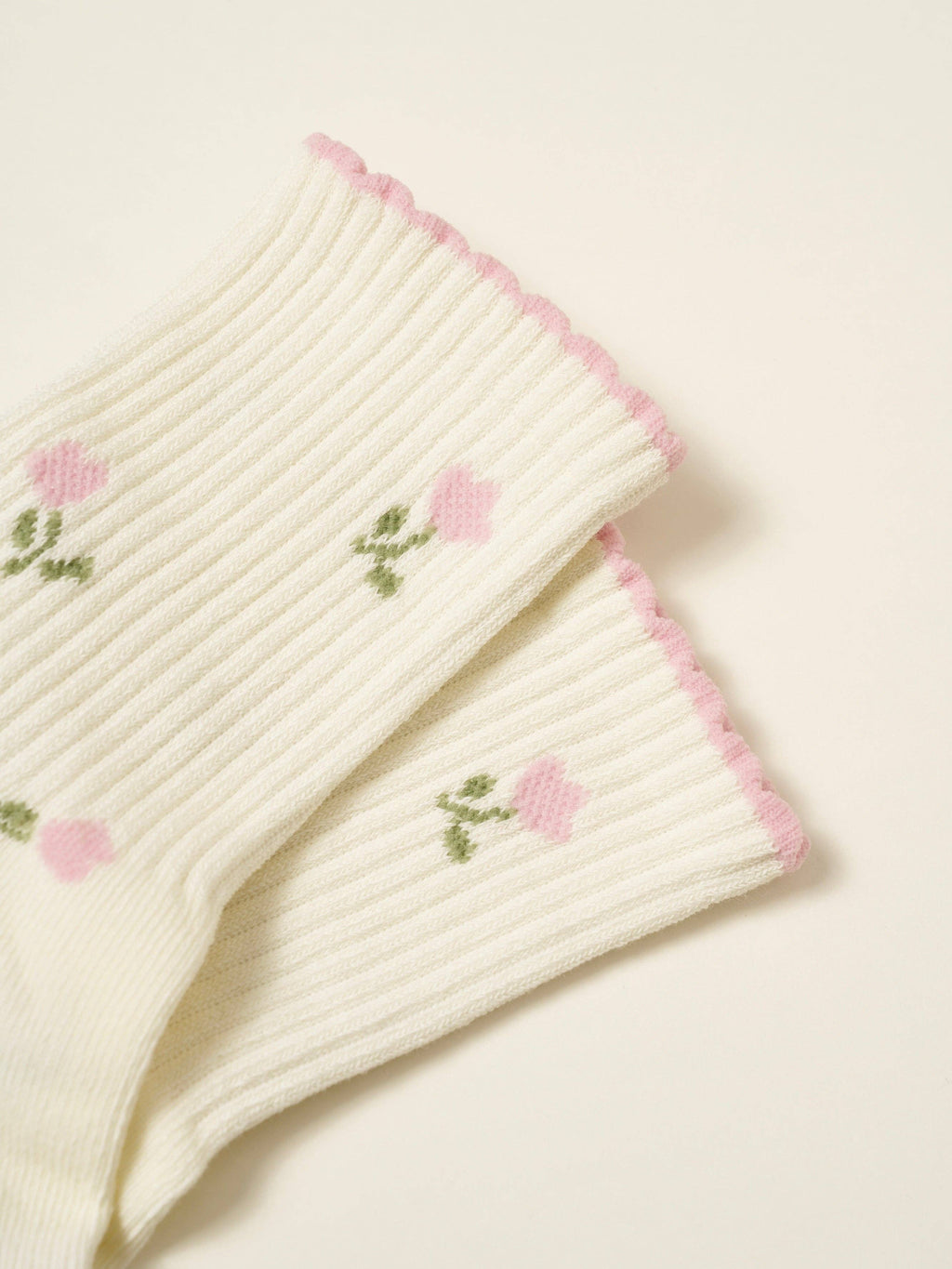 Close view of the ribbed cuff, scalloped pink edge and embroidered tulips