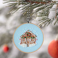 Finished embroidery hoop ornament of a gingerbread house on pale blue, hanging on a snowy pine