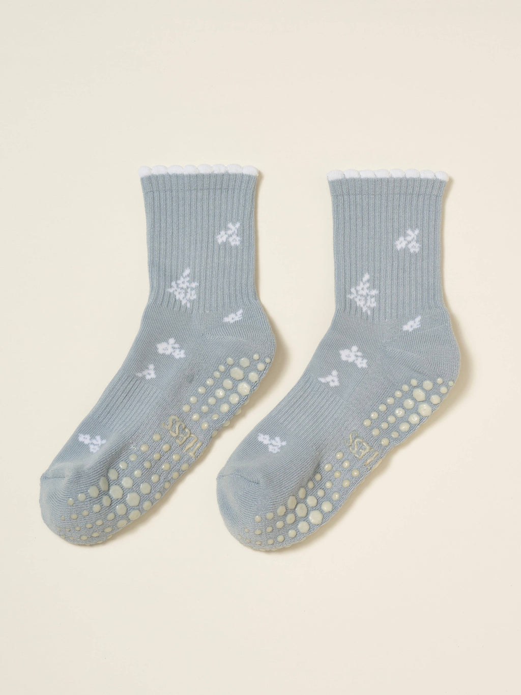 Pair of pale blue snowflake socks laid flat with cream grip soles