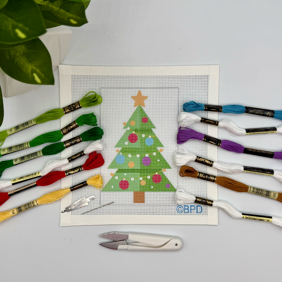 Christmas Tree needlepoint kit: a painted canvas of a green tree with ornaments and a gold star, with threads and tools