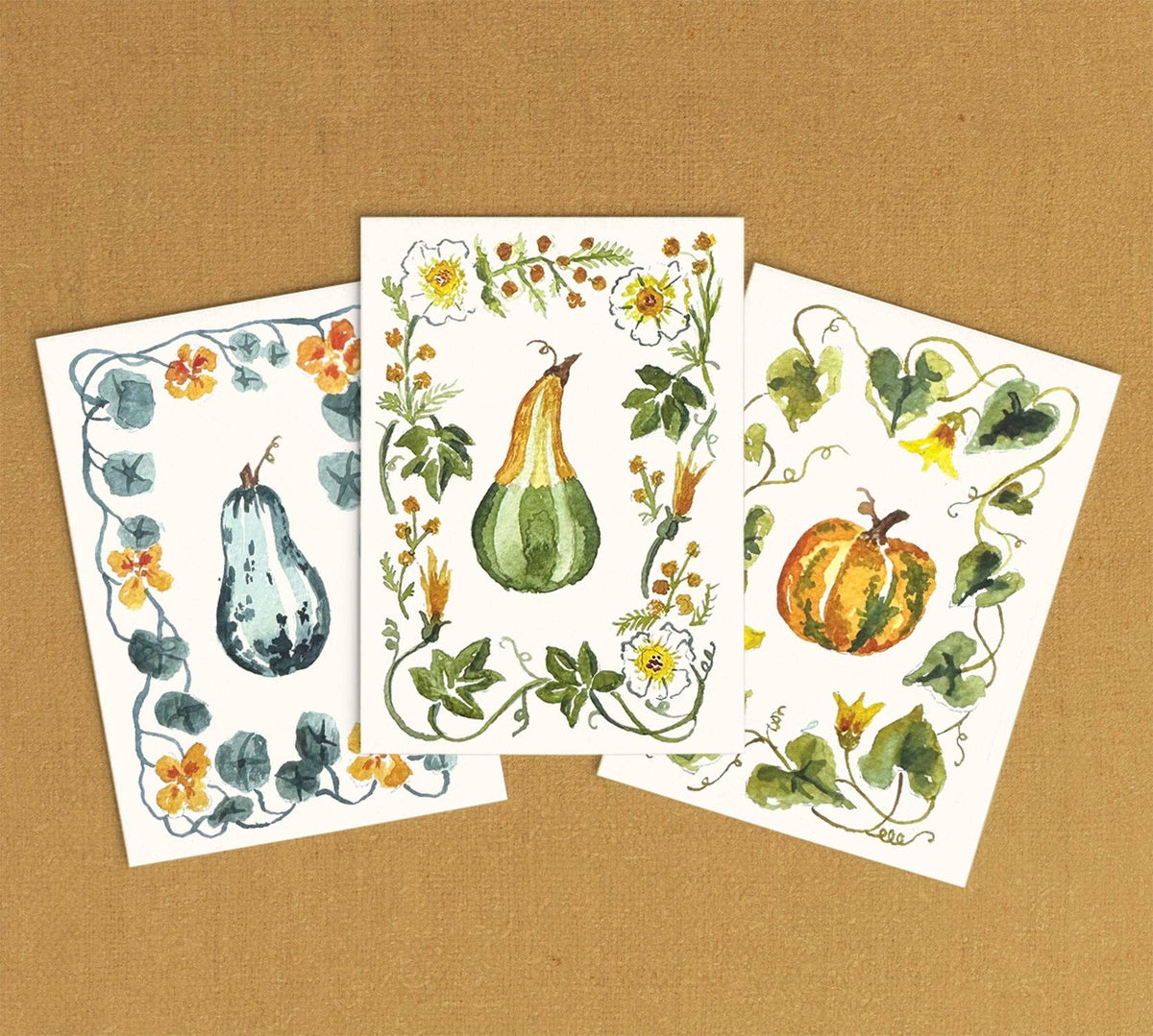 Three finished mini paintings: a blue gourd, a green gourd and a pumpkin, each in a leafy border