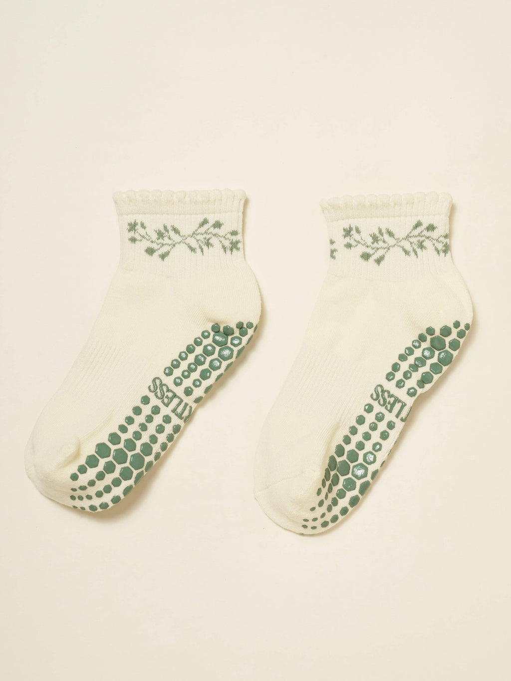 Pair of cream cropped crew grip socks with a green garland at the cuff and green grip soles