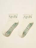 Pair of cream cropped crew grip socks with a green garland at the cuff and green grip soles