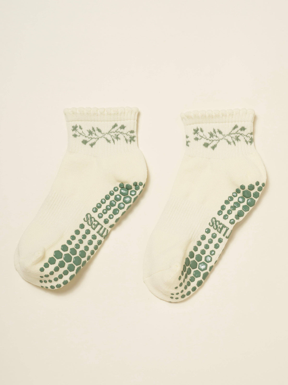 Pair of cream cropped crew grip socks with a green garland at the cuff and green grip soles