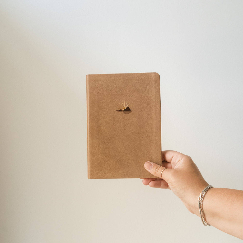 Hand holding the taupe notebook
