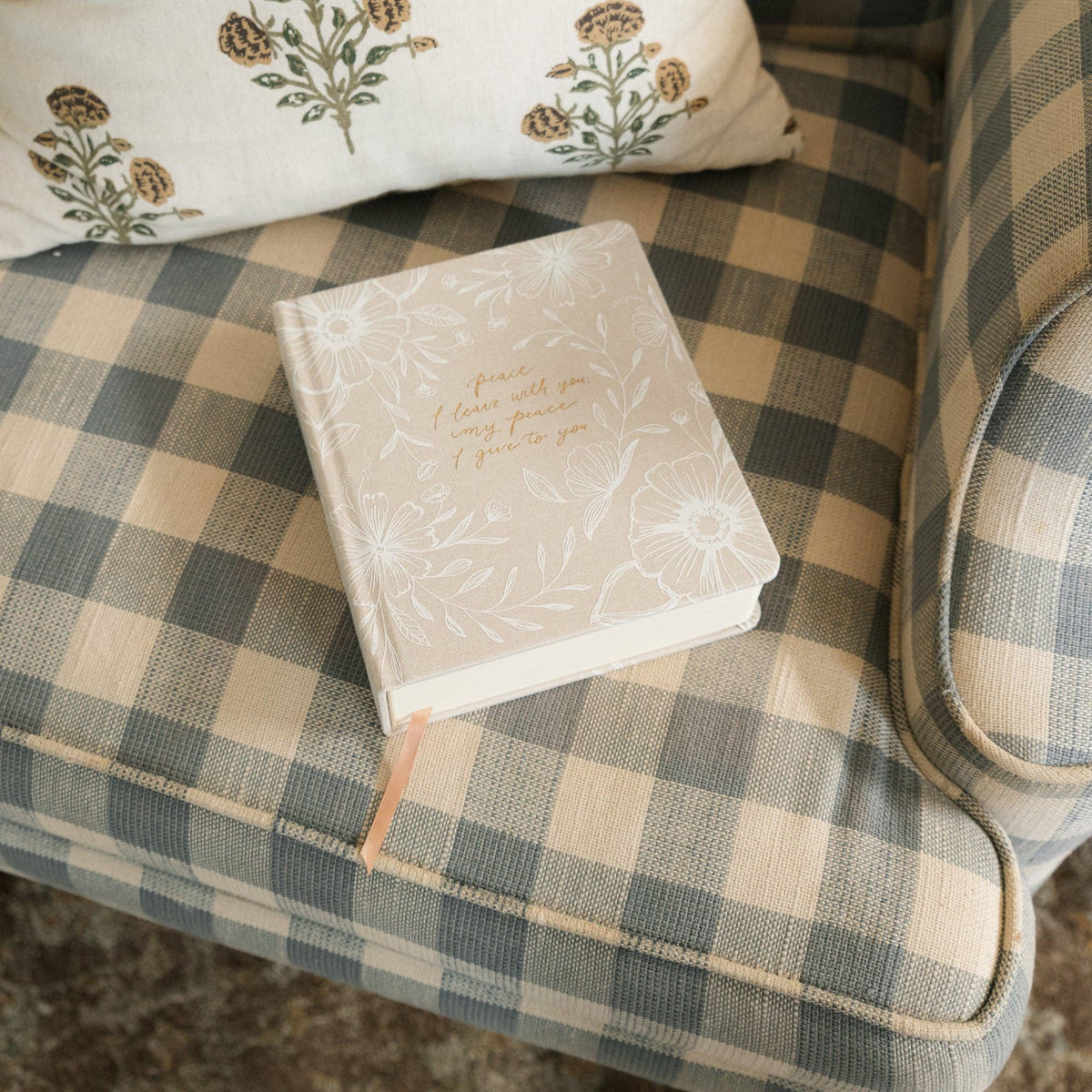 The cream floral journal resting on a checked armchair