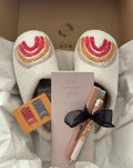 Study box contents packed in tissue: white slippers with a rainbow design, a My Prayer List pad, two pastel highlighters and a floral pen tied with a black ribbon, and Pray and Love magnetic bookmarks