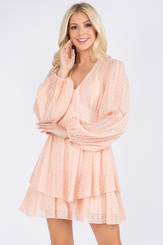 Closer front view of the peach dress's V-neck, fitted waist and sheer dotted sleeves