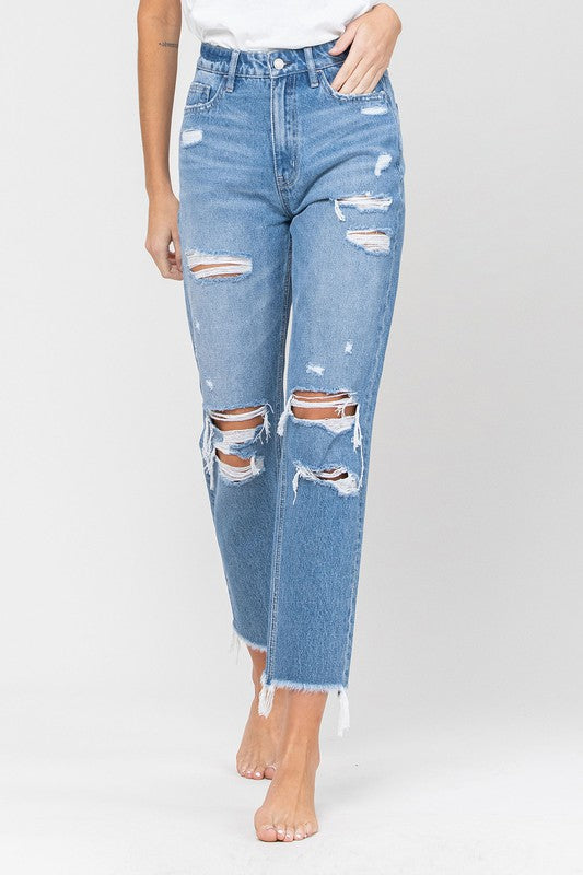 Close front view of the distressed jeans: ripped knees and a raw, frayed hem