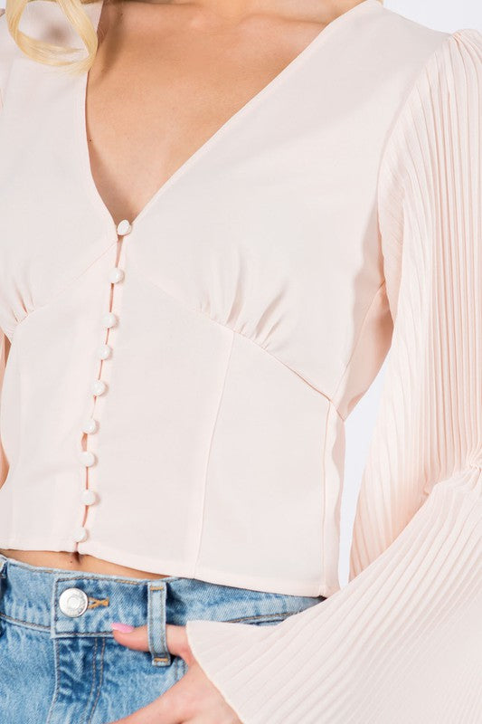 Close view of the blush top's covered buttons, gathered bust and pleated sleeve