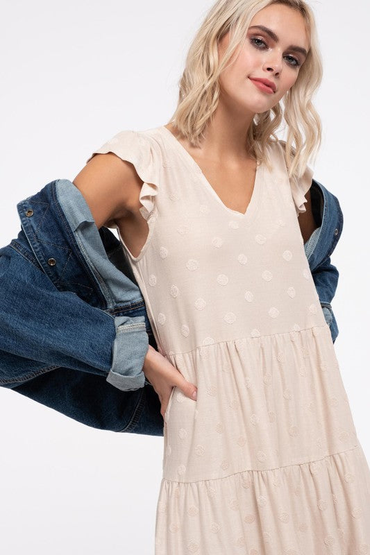 Close view of the cream dress's V-neck, flutter sleeve and subtle dot texture