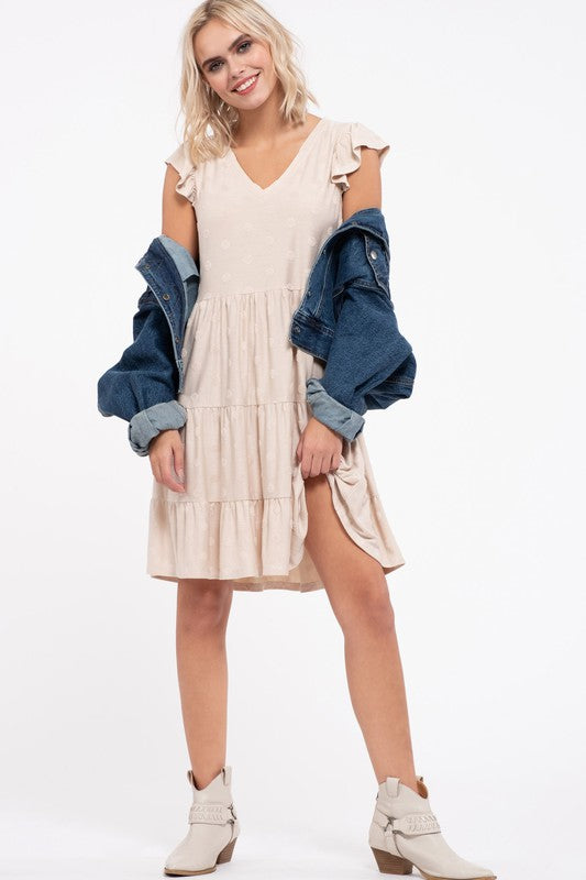 The cream tiered dress styled with a denim jacket over the shoulders