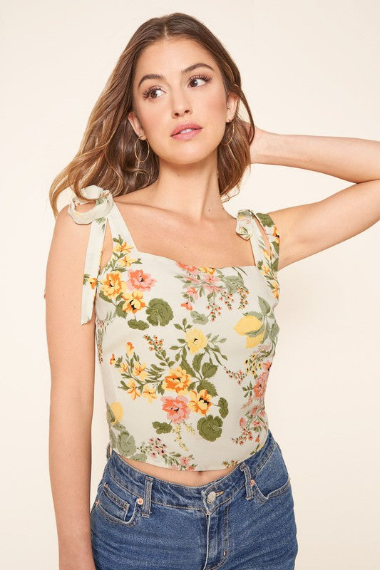 Close front view of the floral top's square neckline and bow-tie straps
