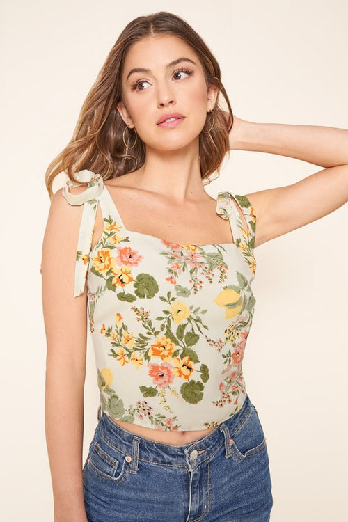 Close front view of the floral top's square neckline and bow-tie straps