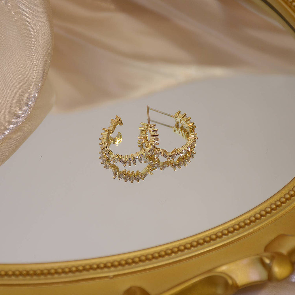 The gold crystal hoops resting on a gold-framed mirror