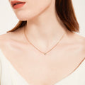 Dainty gold chain necklace with a single small crystal pendant, worn