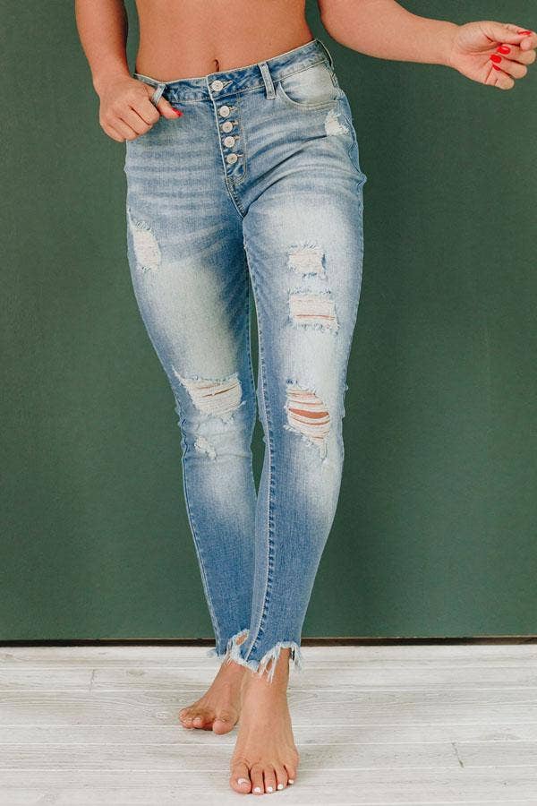 Close front view of the jeans' button fly, ripped knees and frayed hems
