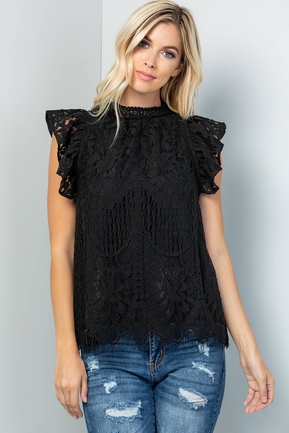 Front view of the black lace top worn with distressed jeans