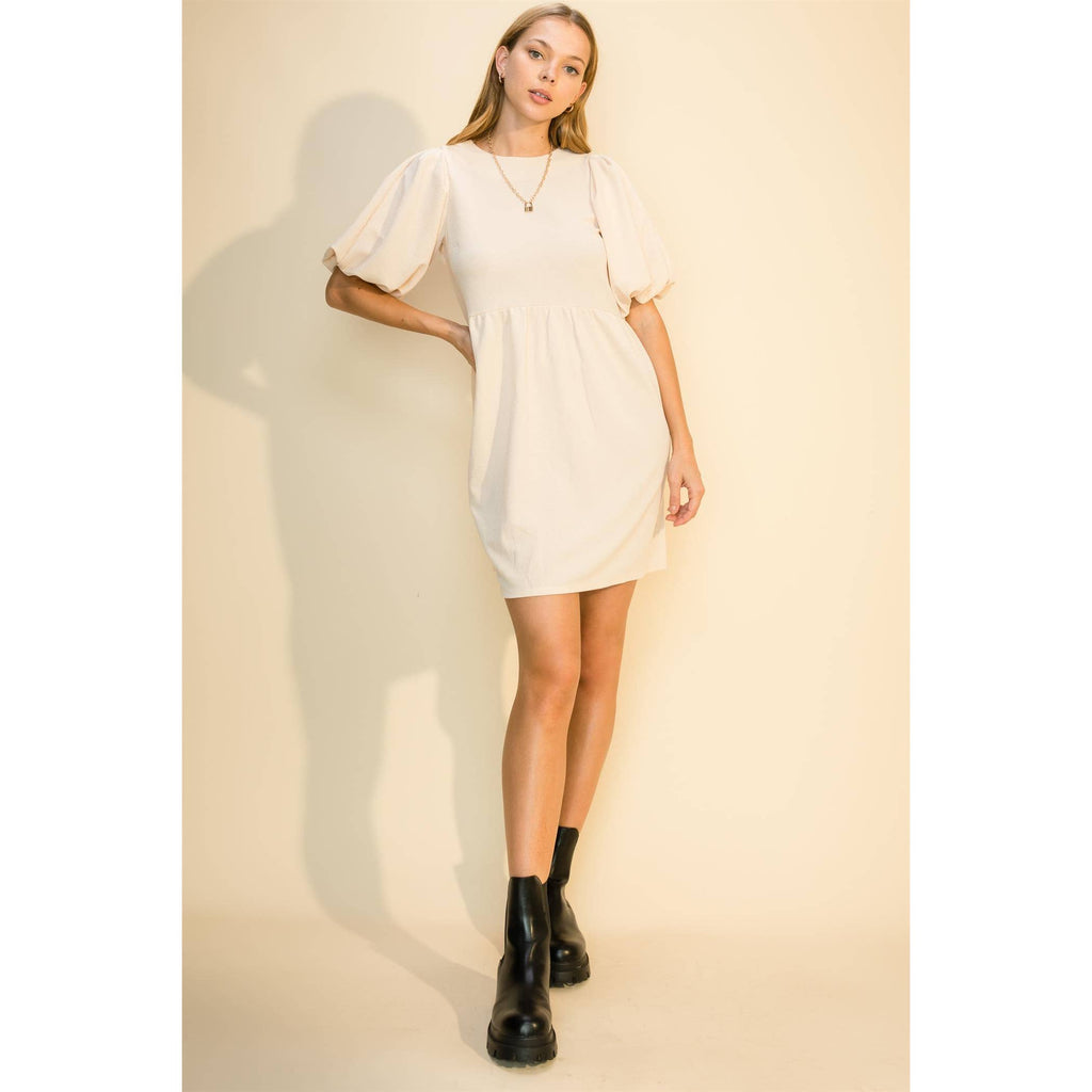 Cream babydoll mini dress with a round neck and puff sleeves, worn with black boots