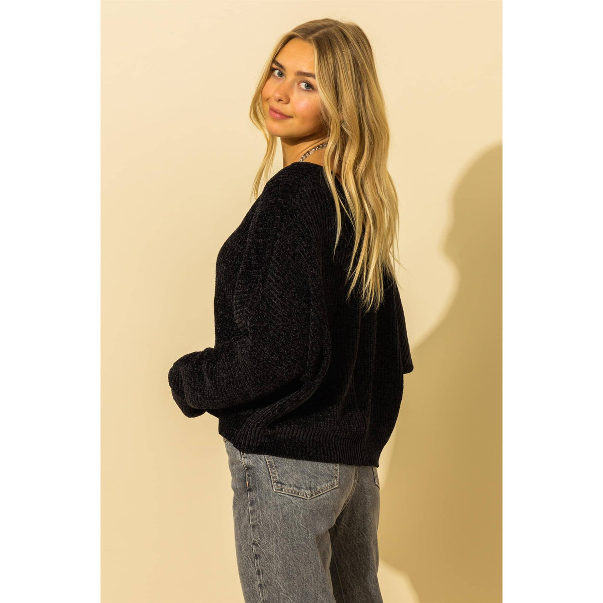 Side view of the black sweater's dropped shoulders and ribbed hem