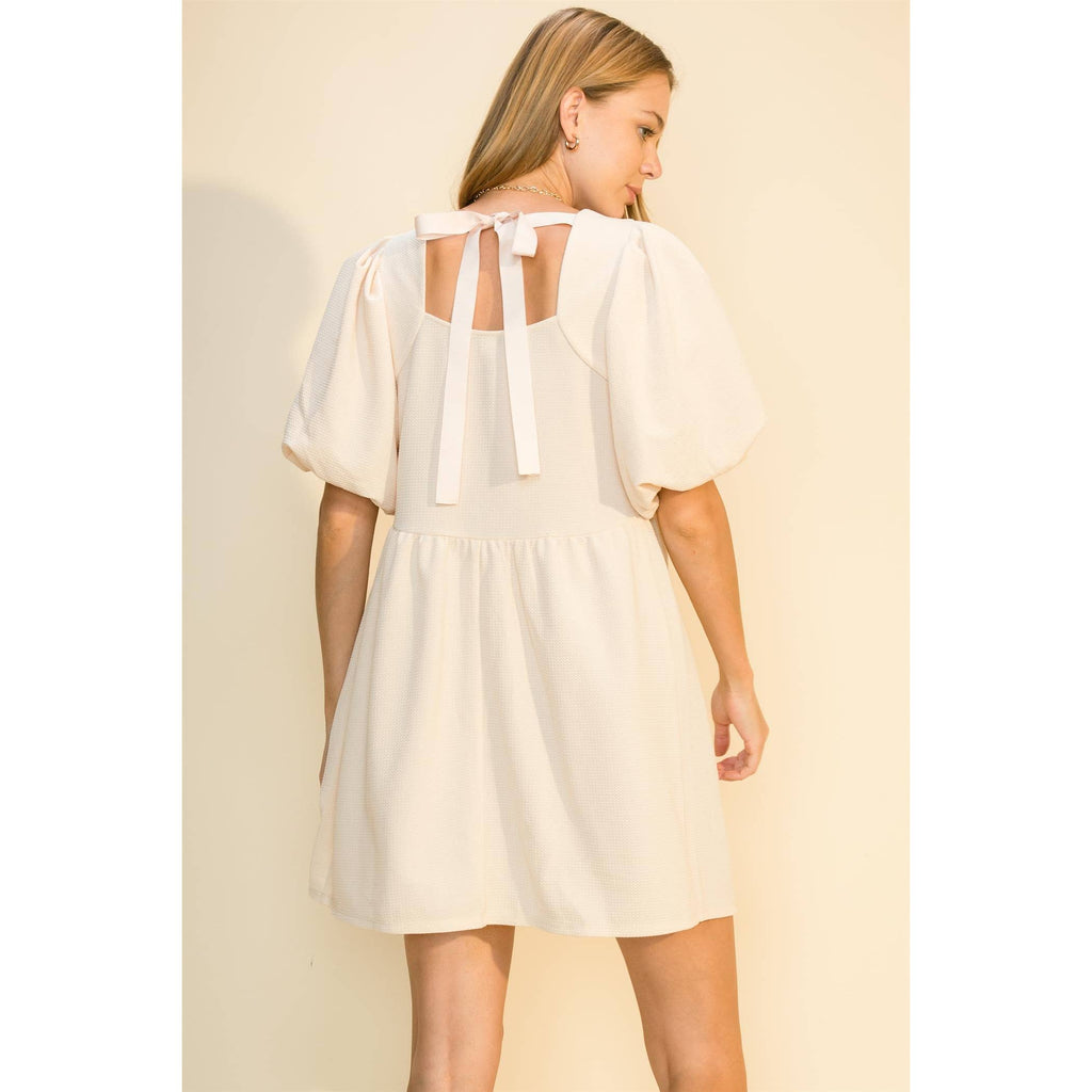 Back view of the cream dress showing the open back and bow ties