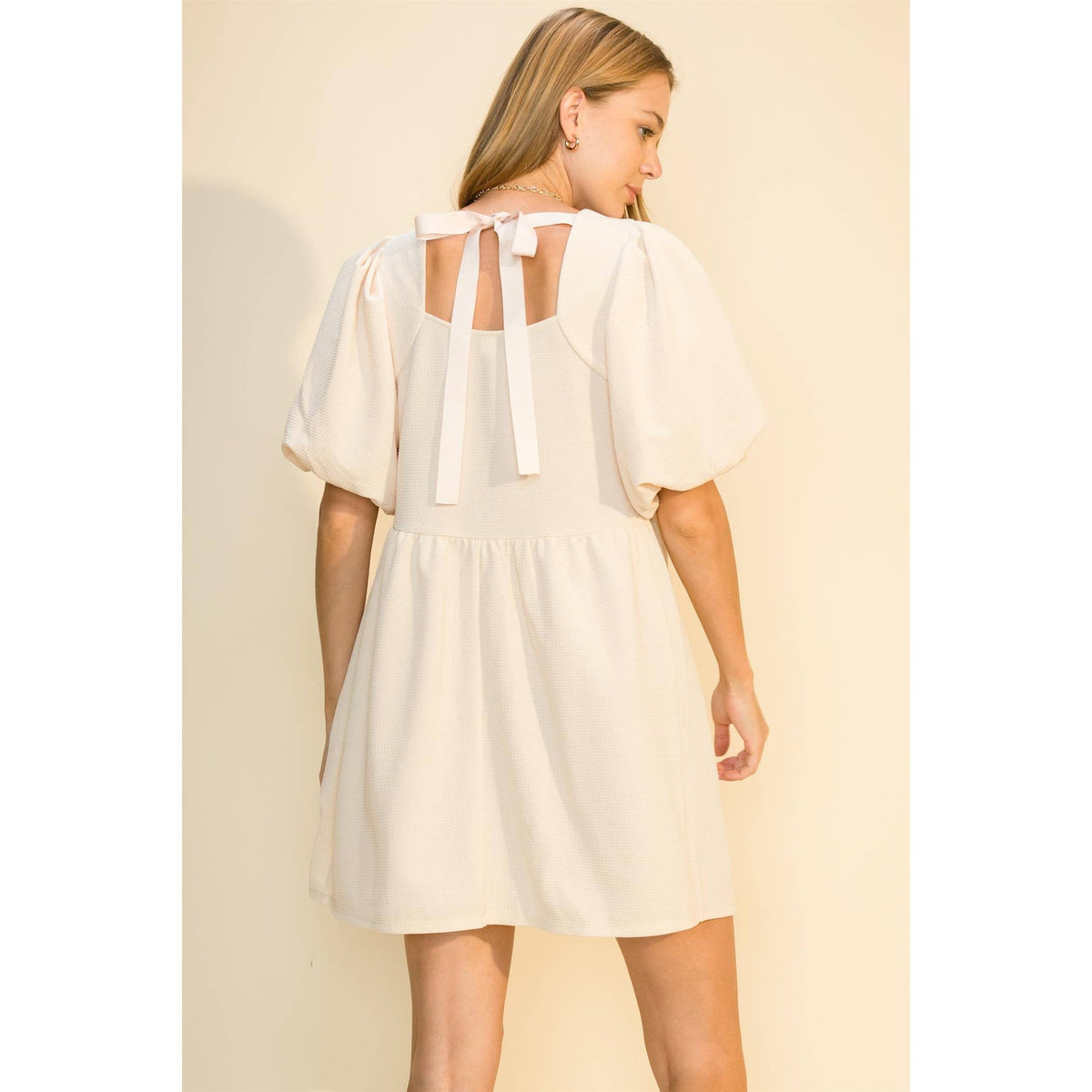 Back view of the cream dress showing the open back and bow ties