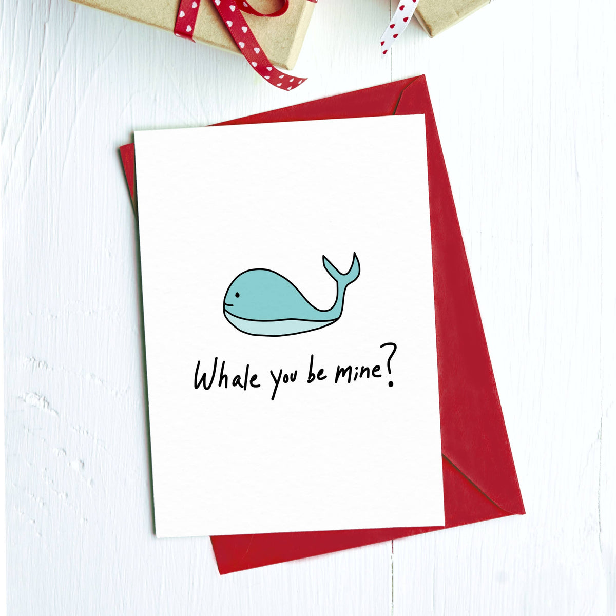 Greeting card with a cartoon blue whale and "Whale you be mine?" on a red envelope